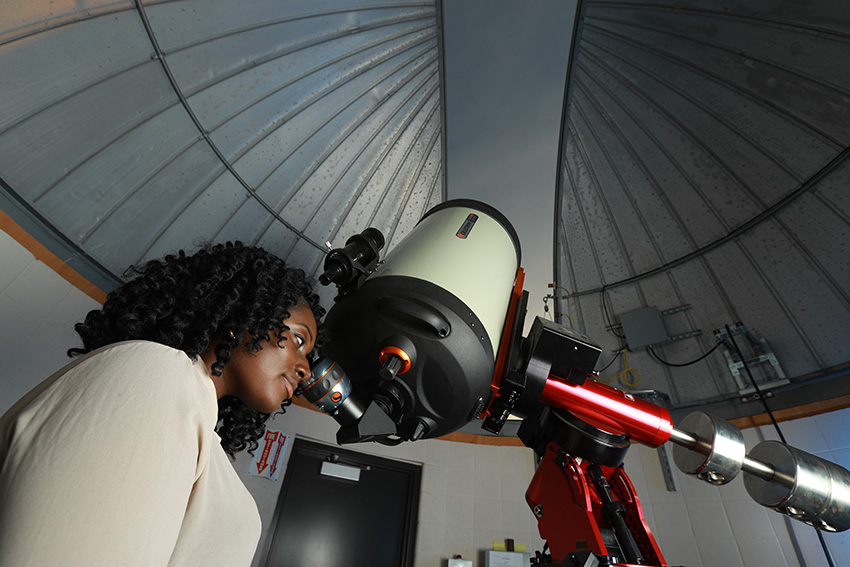 A UToledo astronomer looking into a telescope